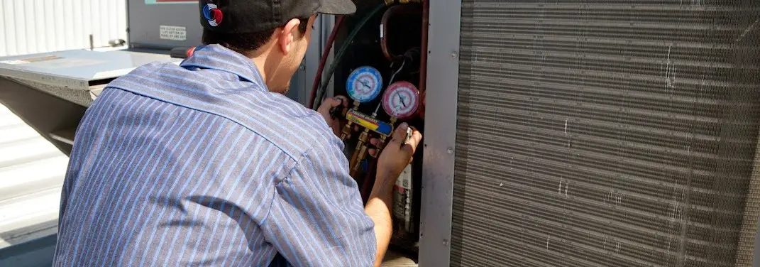 HVAC technician servicing a condenser unit in Big Spring